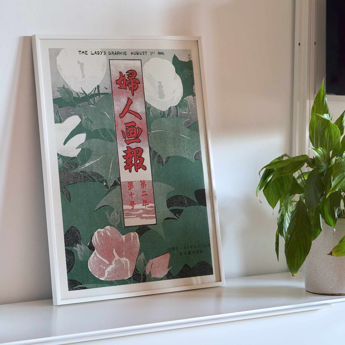 The Lady Graphic by Mitsutani Kunishiro poster with white flowers, green leaves, red lettering, and botanical foliage, with wooden magnetic frame on white background