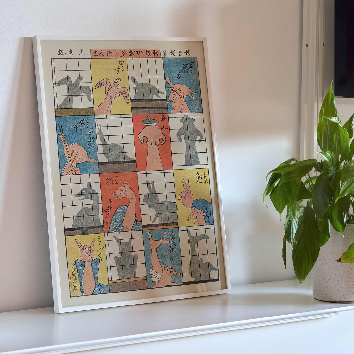 Utagawa Hiroshige Eight Shadow Figures poster with colorful hand gestures and ukiyo-e style panels, framed and displayed in modern living room decor