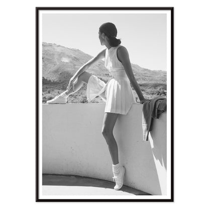Fashion model in tennis outfit seated on wall looking at mountains by Toni Frissell poster artwork, with black aluminium frame on white background