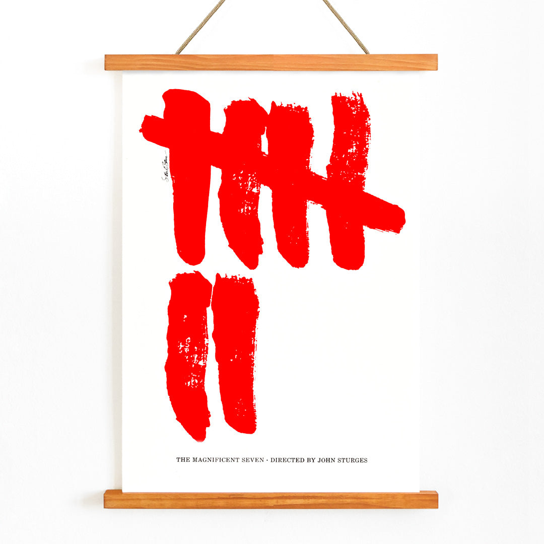 Minimalist movie poster for The Magnificent Seven by Saul Bass with bold red brushstroke tally marks on white background, with wooden magnetic frame on white background