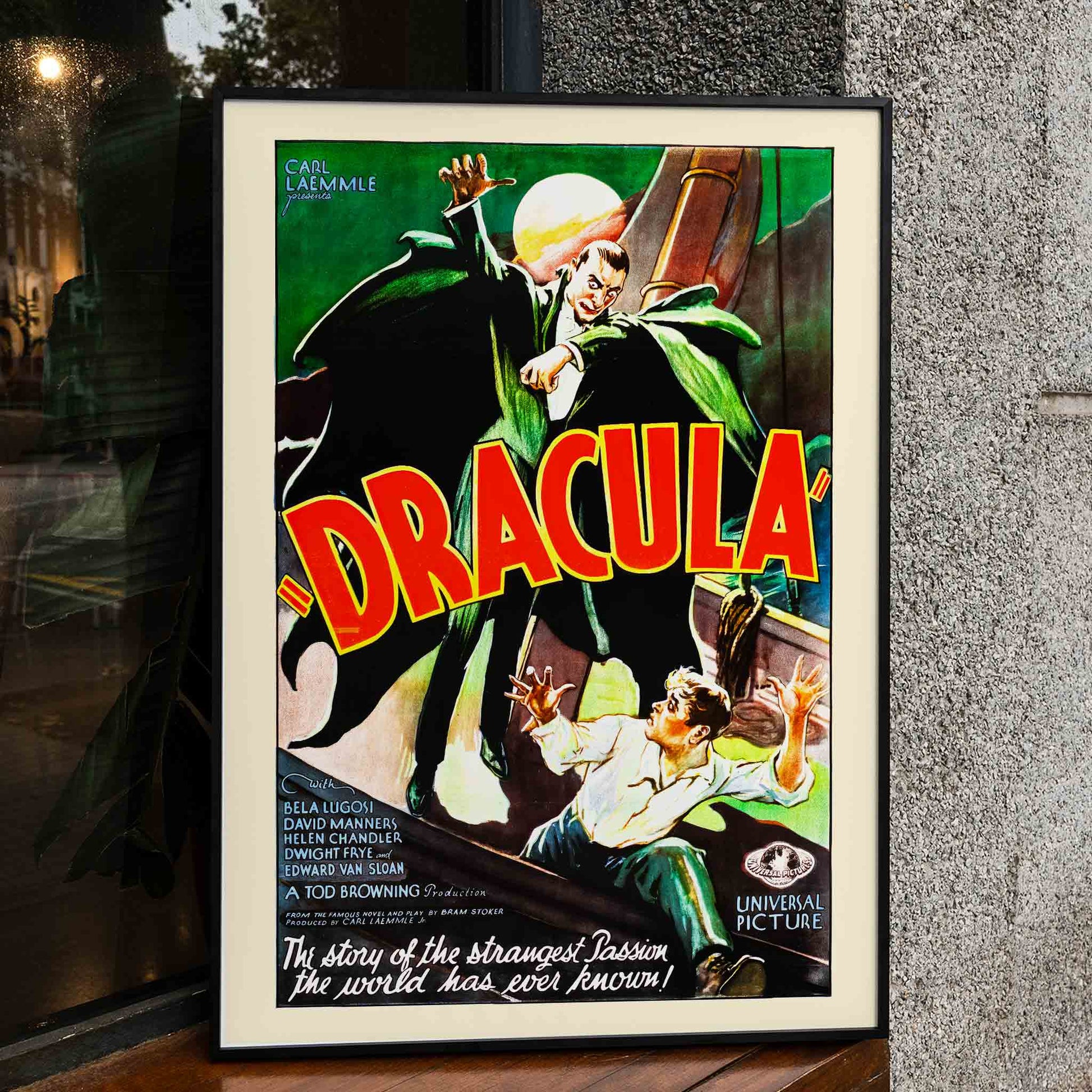 Dracula movie poster by artist showing a menacing Dracula in a green cloak pursuing a terrified man with a full moon in the background, framed and displayed in home decor