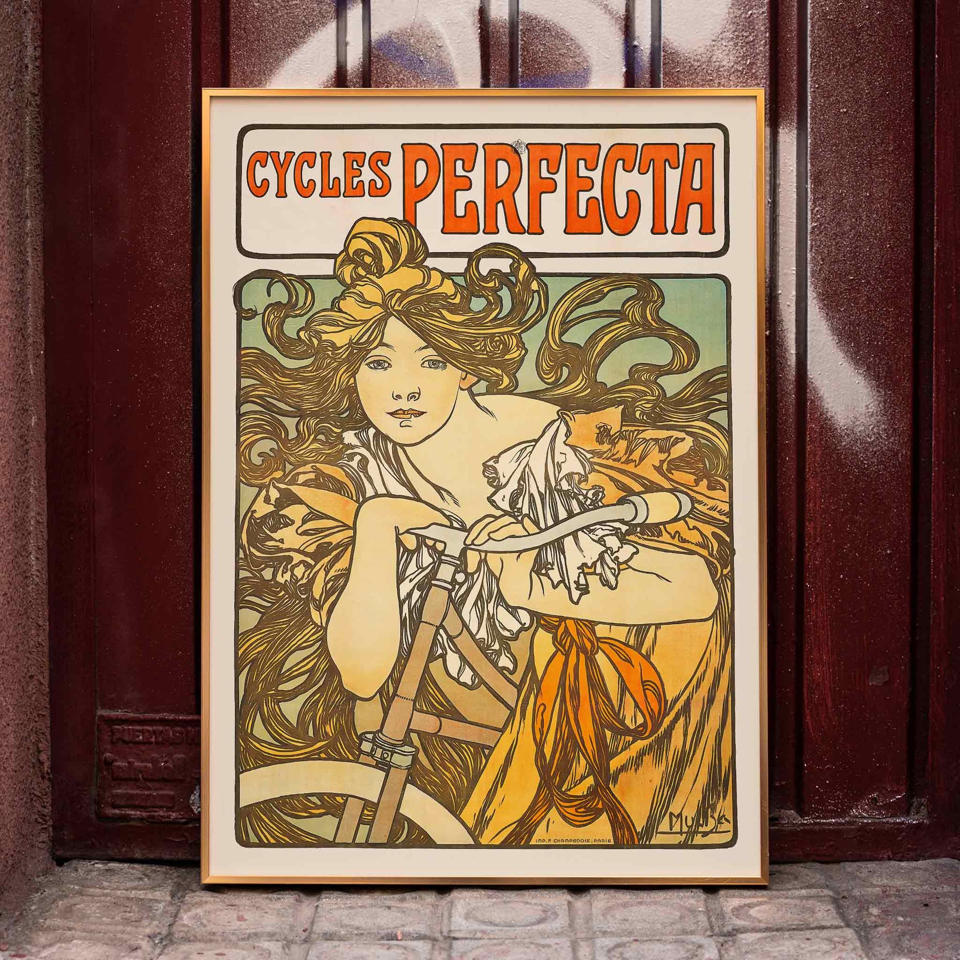 Art Nouveau poster of a woman with flowing hair riding a bicycle with decorative floral design by Alphonse Mucha for Cycles Perfecta, framed and displayed in home decor