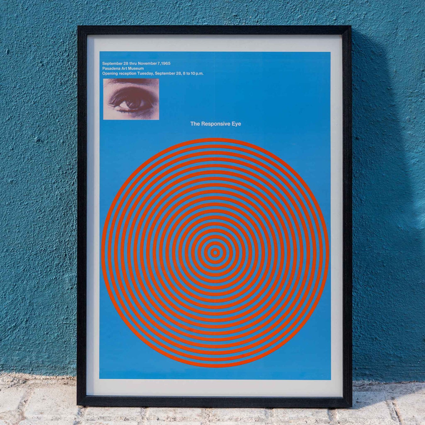 Op art poster with blue and red concentric circles and eye detail from The Responsive Eye by Patrick Blackwell, framed and displayed in home decor