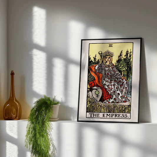 The Empress Tarot card by Rider Waite featuring a crowned woman seated on a throne in a lush natural setting holding a scepter with a crown of stars, framed and displayed in home decor
