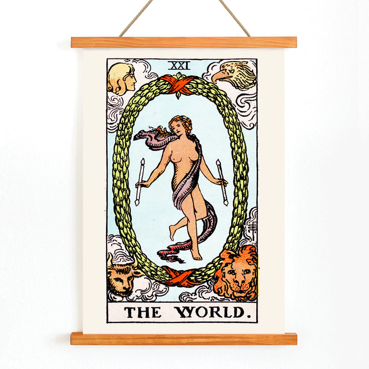 The World Tarot card by Rider Waite showing a central figure within an oval wreath surrounded by four figures representing the fixed signs, with wooden magnetic frame on white background