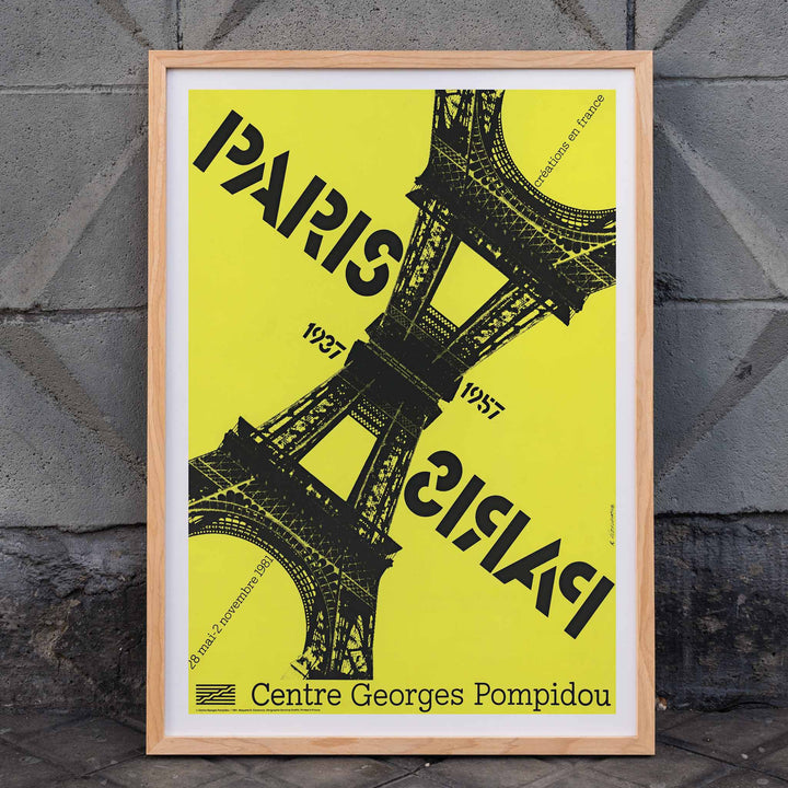 Roman Cieślewicz Paris-Paris 1937-1957 poster with yellow background black Eiffel Tower and mirrored typography, framed and displayed in home decor